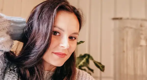 Portret Katarzyny Ciepelewskiej w swetrze, z włosami opadającymi na twarz.