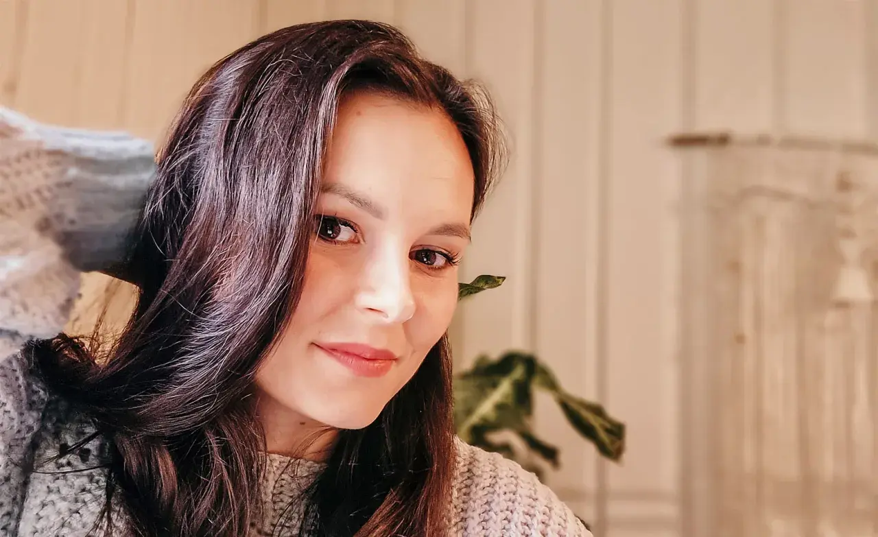 Portret Katarzyny Ciepelewskiej w swetrze, z włosami opadającymi na twarz.