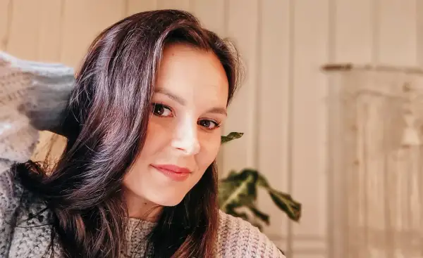 Portret Katarzyny Ciepelewskiej w swetrze, z włosami opadającymi na twarz.
